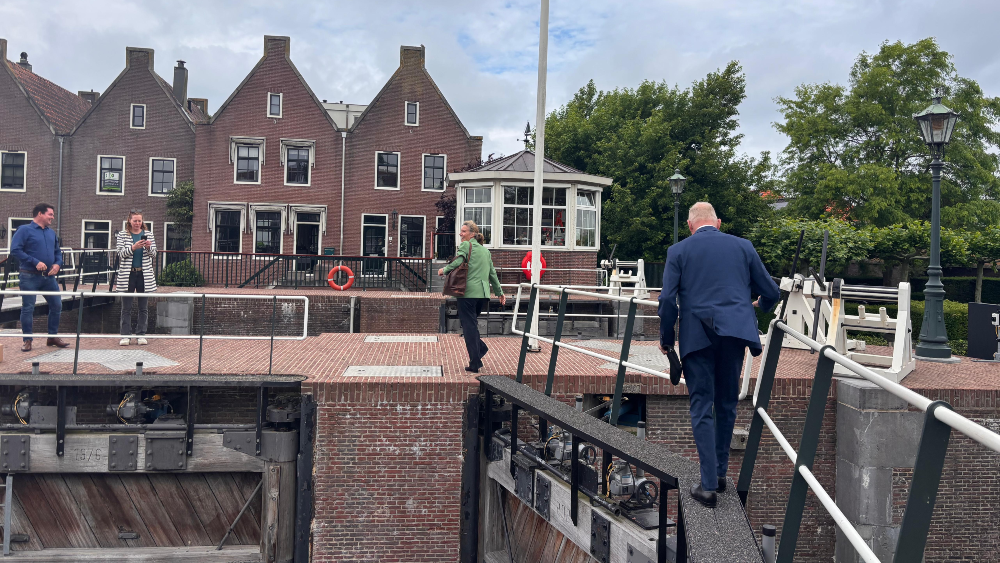 Over een smalle brug lopen de aanwezigen naar het midden van de sluis